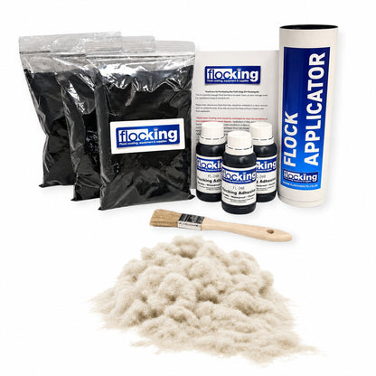 A Flocking Adhesive Kit by Flocking on a white background, containing three bags of black flocking powder, a tube flocking applicator, three small bottles of flocking adhesive, a printed instruction sheet, a wooden-handled brush, and a pile of Raw white flocking fibres in the foreground.